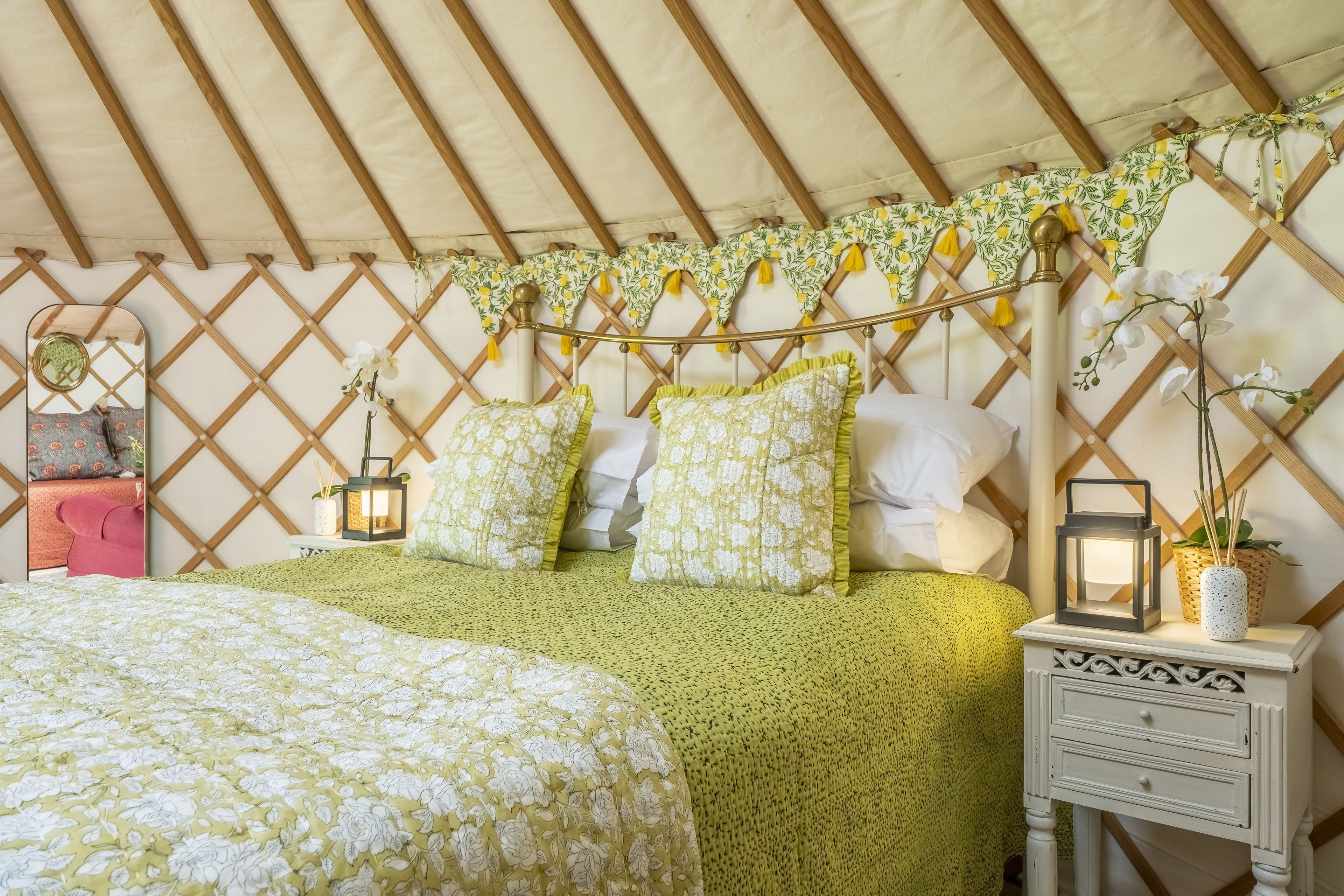 A cozy tent with a bed, a nightstand, and a mirror.