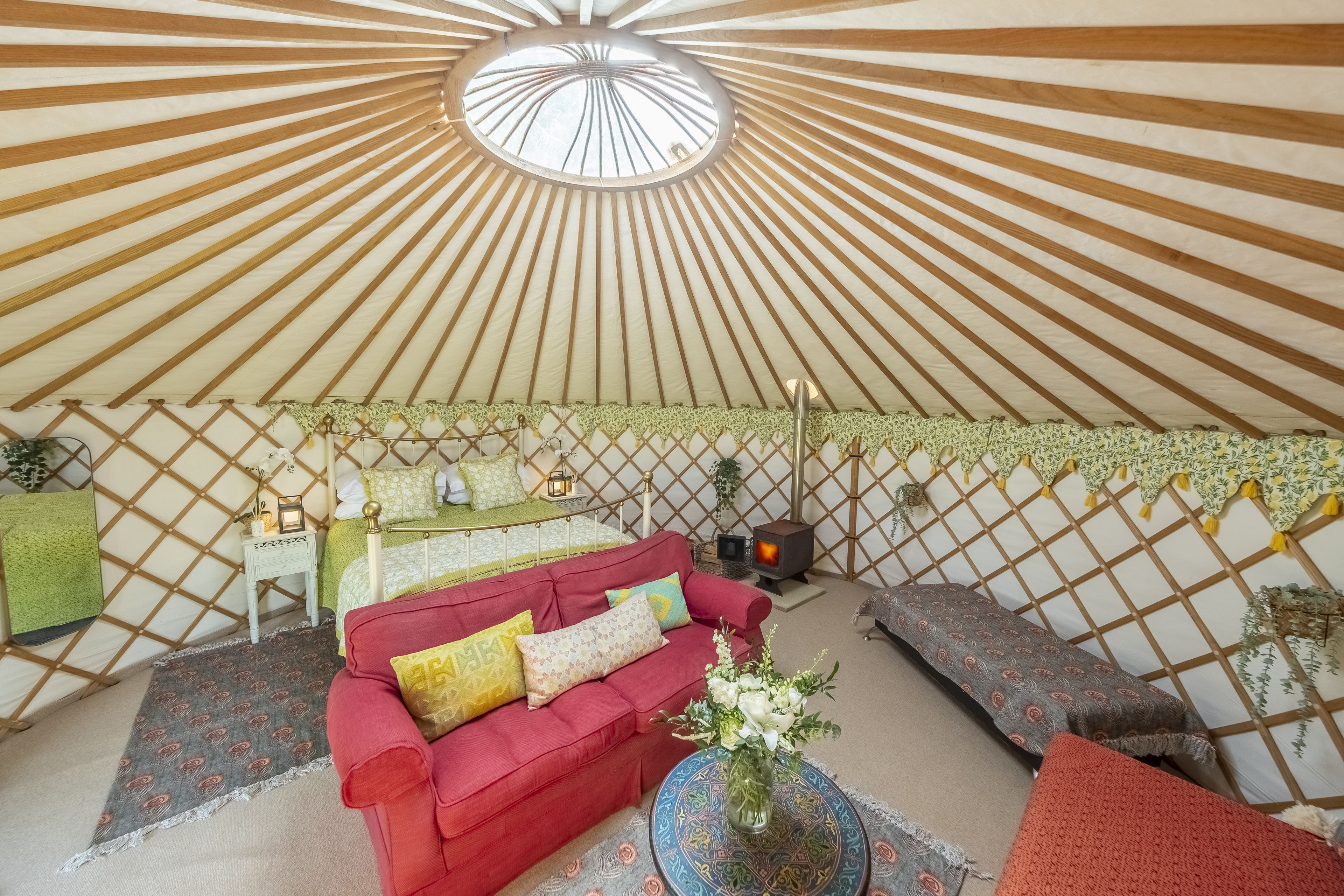 A yurt interior with a red sofa, a green table, and a patterned rug.