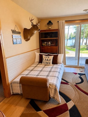 A bedroom with a bed, a mounted deer head, a bookshelf, and a view of a lake. - Private, Beautiful Lake Front Home in Prime Location  (Wetmore)
