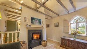 A cozy living room with a fireplace, a staircase, and a large window. - A fairy-tale luxurious cottage - The Tea Caddy (Colchester)