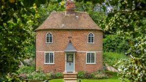 A brick house with a central door, two windows on each side, and a small porch. - A fairy-tale luxurious cottage - The Tea Caddy (Colchester)