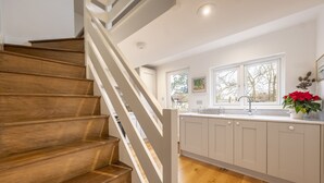 A modern kitchen with wooden stairs, white cabinets, and a window with a view. - Barn conversion with private pool - Yew Tree Barn (Colchester)