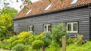 A dark wooden house with a tiled roof and three windows. - Barn conversion with private pool - Yew Tree Barn (Colchester)