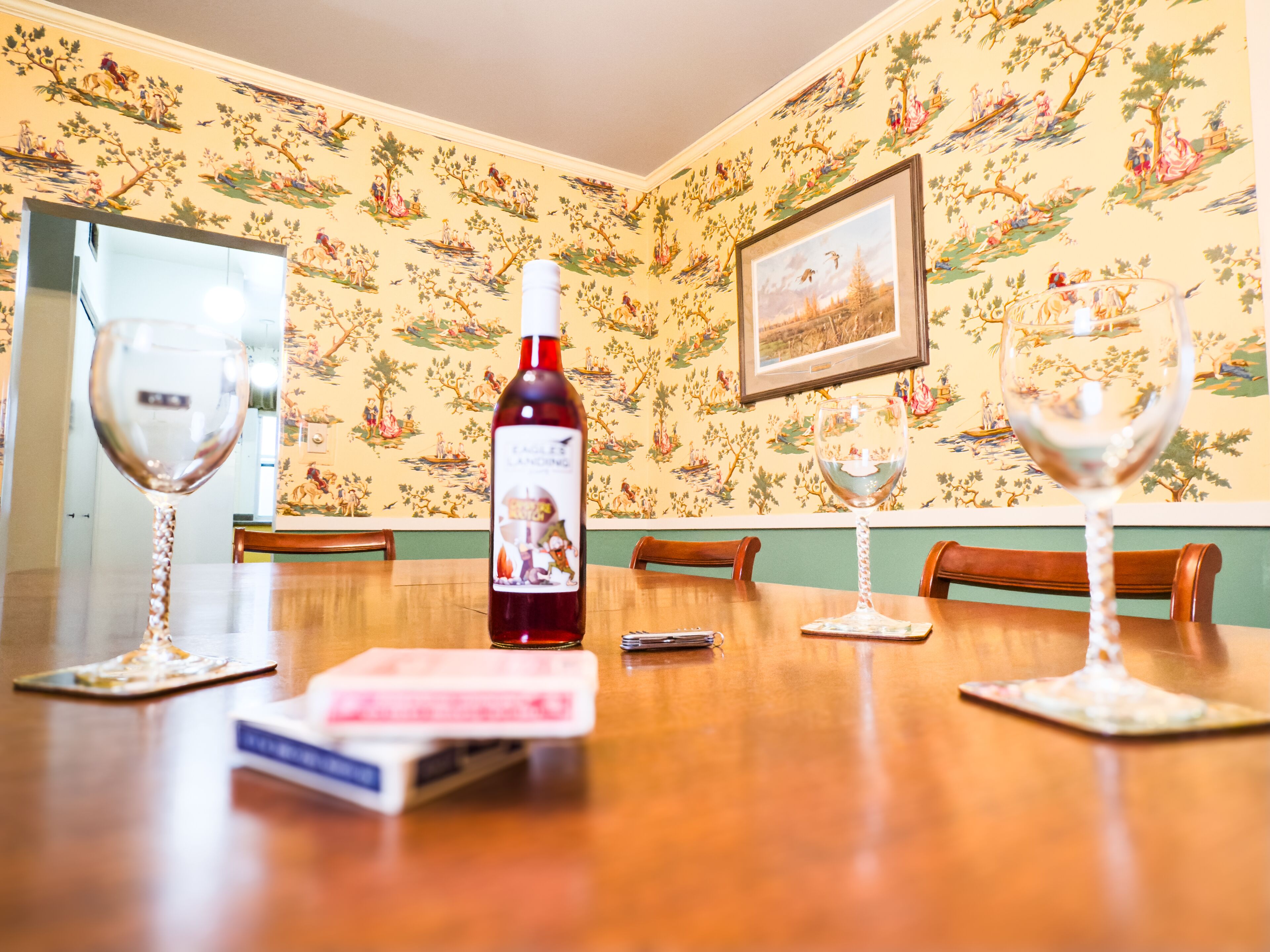 A dining table with a bottle of wine, two wine glasses, and a menu.