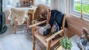 A cozy cabin interior with a wooden desk, a chair with a fur throw, a woven chair, and a statue. - Stunning home in åseral with sauna (Åseral)
