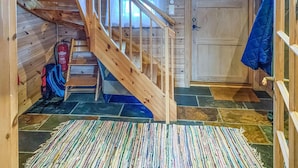 A wooden staircase leading to a room with a fire extinguisher, a blue jacket hanging, and a patterned rug on the floor. - Stunning home in åseral with sauna (Åseral)