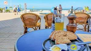 Une table avec du pain, du beurre et une bouteille de vin Blanche de Narbonne dans un café en bord de mer.