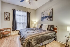 Relax in a serene bedroom with a large bed, bedside table, and comfortable chair.