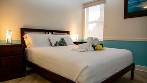 A neatly made bed with white linens, a wooden headboard, and a nightstand with a lamp. - Lovely Studio Apartment in Downtown Albany (Albany)