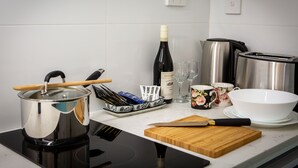 A kitchen with a stove, a pot, a bottle of wine, a cutting board, a knife, a toaster, and a coffee maker. - Lovely Studio Apartment in Downtown Albany (Albany)