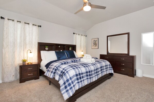 A bedroom with a bed, nightstands, a dresser, a ceiling fan, and a window. - Rammies 3 bedroom Home W/Pool Access (Fulshear)