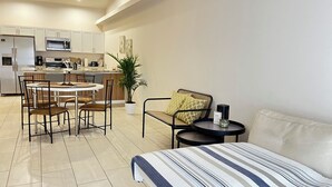 Un appartement moderne comprenant un coin repas, une kitchenette et un espace de vie avec un lit et des sièges.