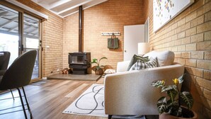 Una sala de estar acogedora con chimenea, un sofá, un sillón y una planta en maceta.