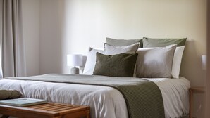 Una habitación de hotel ordenada con una cama, una mesita de noche y una lámpara.
