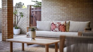 Un rincón al aire libre acogedor con sofá, una mesa de madera y una planta en maceta.