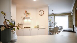 Una cocina moderna con armarios blancos, un reloj y un comedor con mesa y sillas.