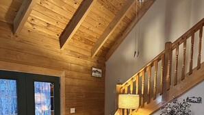 Interior de madera con una escalera, sillas de cuero y una vista a través de una puerta.