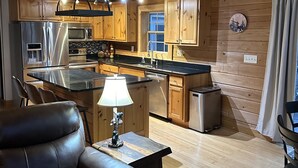 Una cocina acogedora de estilo cabaña con armarios de madera, un refrigerador de acero inoxidable y un microondas.