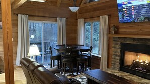 Un acogedor interior de cabaña de madera con un sofá de cuero, una mesa de comedor y una chimenea.