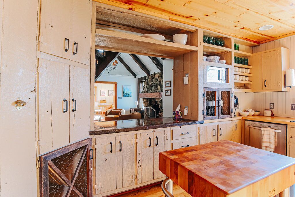 Una cocina rústica con armarios de madera, encimera de madera y pared de piedra.