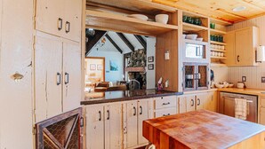 Eine rustikale Küche mit Holzausbau, einer Holz Arbeitsplatte und einer Steinwand.