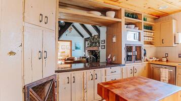 Una cocina rústica con armarios de madera, encimera de madera y pared de piedra.