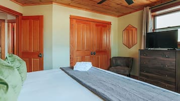 A bedroom with a bed, wooden wardrobe, and a television.