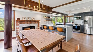 A modern kitchen with a central island, built-in appliances, and a large dining area with wooden tables and chairs. - Lake Reflection Point-Upscale Lake View House! 4 Bed/4.5 Bath! Air Conditioning! (Lake Arrowhead)