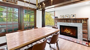 A dining area with a wooden table and chairs, a fireplace, and a sign that reads "LAKE". - Lake Reflection Point-Upscale Lake View House! 4 Bed/4.5 Bath! Air Conditioning! (Lake Arrowhead)