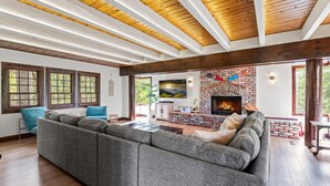 A spacious living room with a large sectional sofa, a fireplace, and wooden beams on the ceiling. - Lake Reflection Point-Upscale Lake View House! 4 Bed/4.5 Bath! Air Conditioning! (Lake Arrowhead)