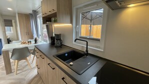 Une cuisine moderne dotée d’un évier encastré, d’une fenêtre et d’un plan de travail sur lequel se trouve une machine à café.