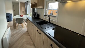 Een moderne keuken met houten kastjes, een zwart aanrecht en een inbouwfornuis.