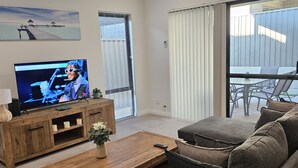 A modern living room with a flat-screen TV, wooden furniture, a coffee table, and a sofa.