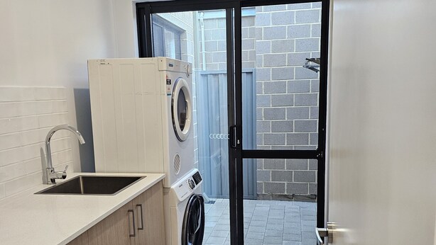 A compact laundry room with a washing machine, dryer, and sink.