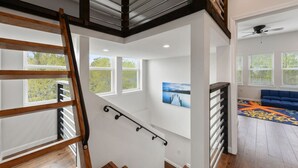 Un interior moderno con una escalera de madera, paredes blancas y un sofá azul.