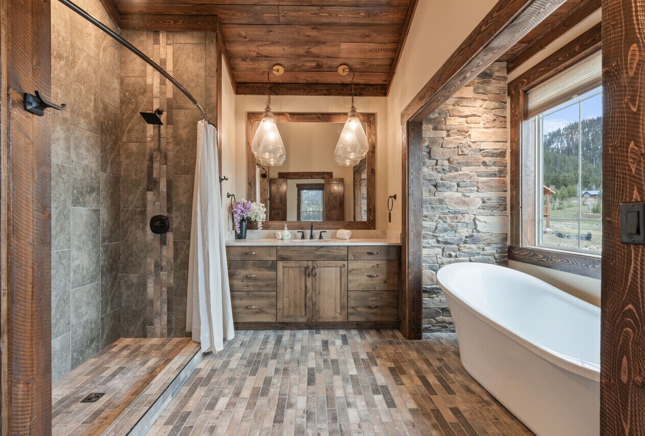 A rustic bathroom with a stone wall, wooden vanity, and a freestanding bathtub.