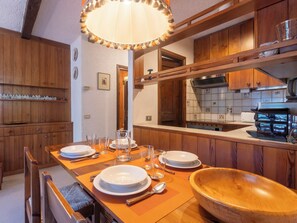 A dining area with wooden furniture, a large wooden bowl, and a table set for four.