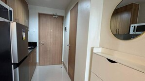 A narrow hallway with a refrigerator, cabinets, and a microwave. - Family suite with 1 bedroom and balcony, stay with us at SMDC Shore 3 Residences (Pasay)