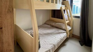 A bunk bed room with a window, air conditioning unit, and a view of buildings outside. - Family suite with 1 bedroom and balcony, stay with us at SMDC Shore 3 Residences (Pasay)