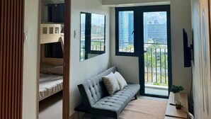 A modern apartment with a sofa, a dining table, and a TV. - Family suite with 1 bedroom and balcony, stay with us at SMDC Shore 3 Residences (Pasay)