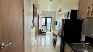 A modern kitchen with wooden cabinets, a black refrigerator, and a stainless steel sink. - Family suite with 1 bedroom and balcony, stay with us at SMDC Shore 3 Residences (Pasay)