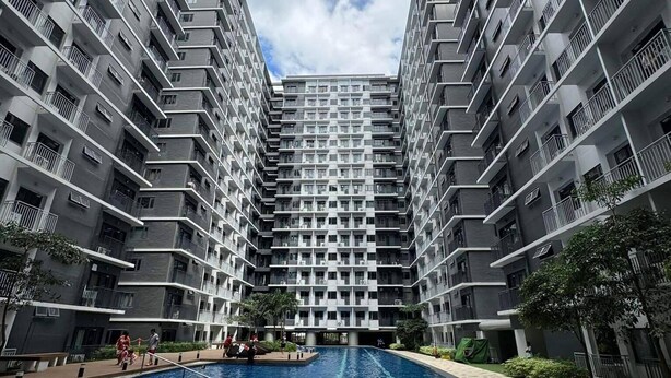 A modern high-rise building with a central swimming pool surrounded by a tiled walkway. - Family suite with 1 bedroom and balcony, stay with us at SMDC Shore 3 Residences (Pasay)
