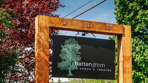 A wooden sign with a tree illustration and text for 'battengreen venue & lodging'.