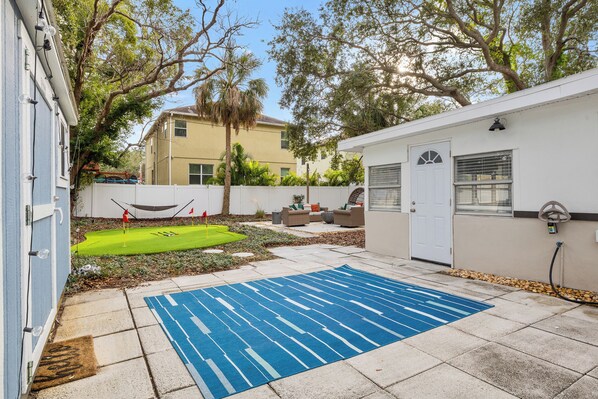 A backyard with a blue mat, a white door, and a small patio area. - Newly Remodeled! Bay Shore Breeze (Tampa)