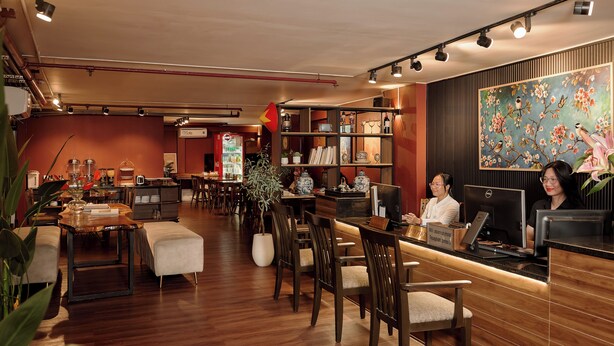 Un restaurant avec des meubles en bois, un comptoir d’accueil et un grand tableau représentant des fleurs accroché au mur.