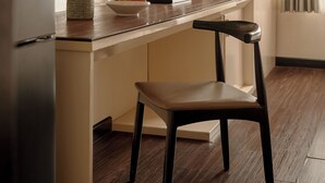 Une cuisine moderne avec un plan de travail en bois, une cuisinière encastrée et un coin repas avec une chaise.