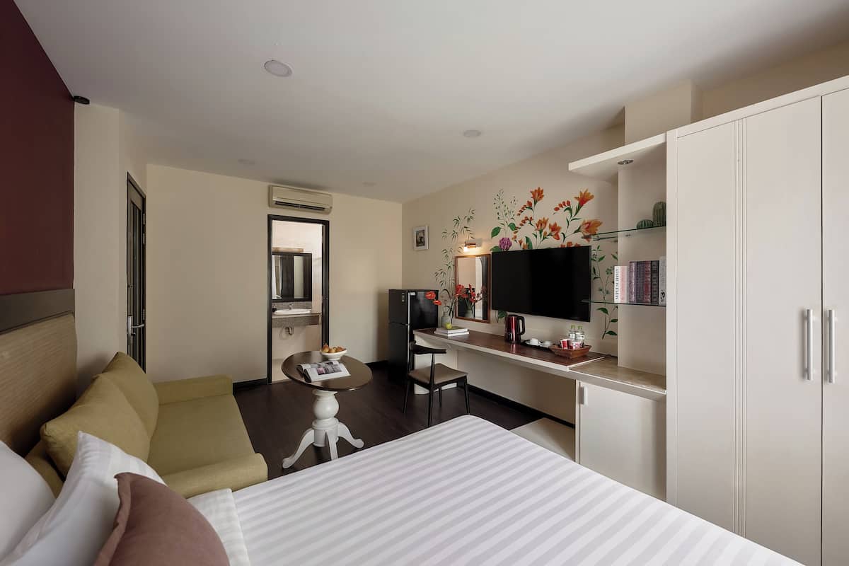 Une chambre d’hôtel comprenant un lit, un canapé, un bureau avec une télévision, une bibliothèque et une armoire.