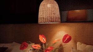 Une chambre d’hôtel avec un lit, une table de chevet avec une lampe, un vase avec des fleurs et un téléphone.