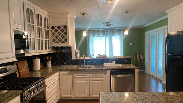 A kitchen with white cabinets, a stainless steel refrigerator, a granite countertop, and a dishwasher. - Beautiful 3Beds in Bridge City! (Bridge City)