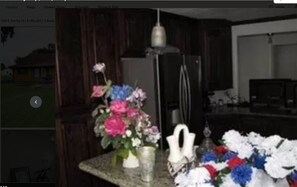 A kitchen with a countertop, a vase with flowers, and a refrigerator. - Beautiful 3Beds in Bridge City! (Bridge City)